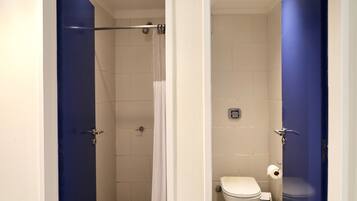 Un baño con ducha, inodoro y barra para toallas.