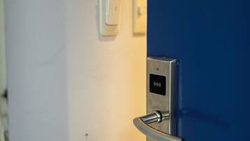 Una puerta con cerradura digital e interruptor de luz en la pared.