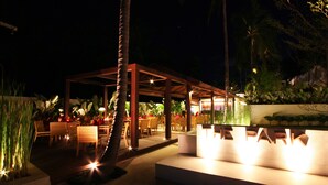 An outdoor dining area with wooden tables and chairs, a covered seating area, and a sign that reads "THE PARK". - The Park Samui (Koh Samui)