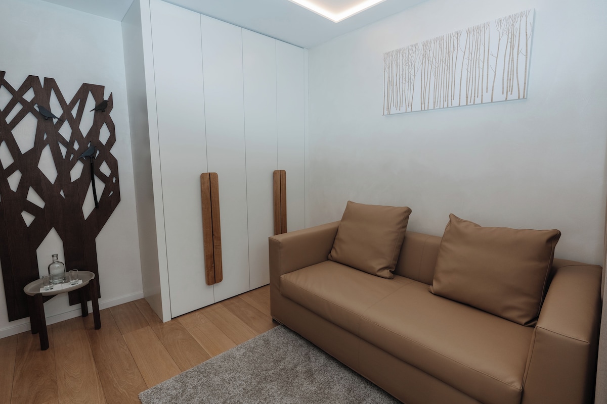 Ein modernes Wohnzimmer mit braunem Sofa, einem Glastisch und einer Holzvertäfelung.