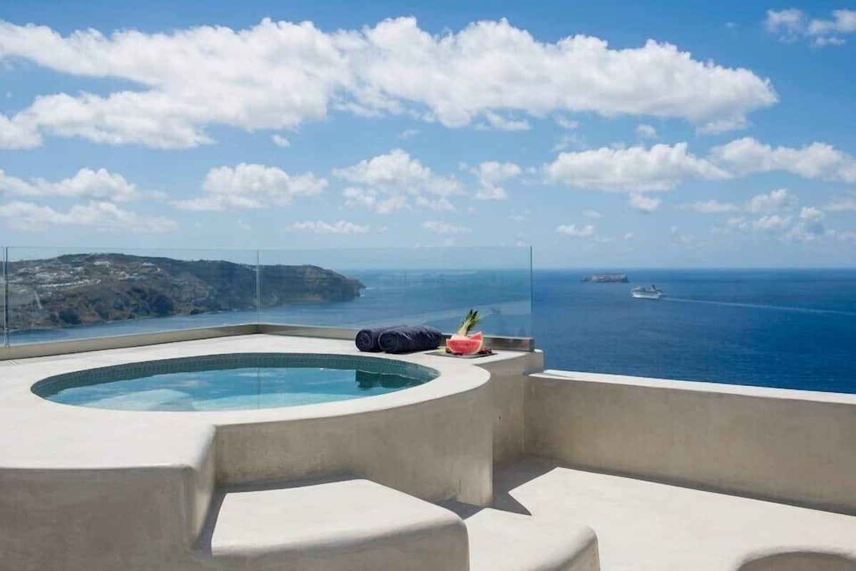 A rooftop pool with a clear view of the sea and a yacht in the distance.