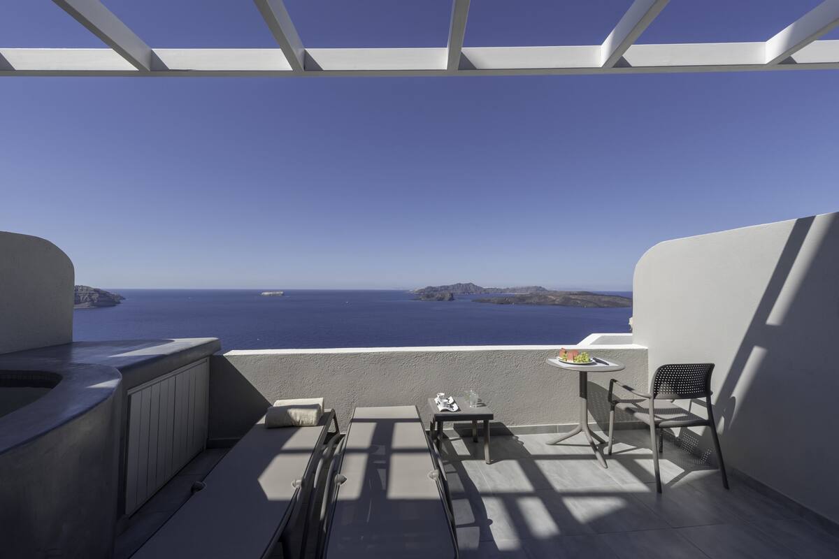 A balcony with a view of the sea, a table, and a chair.