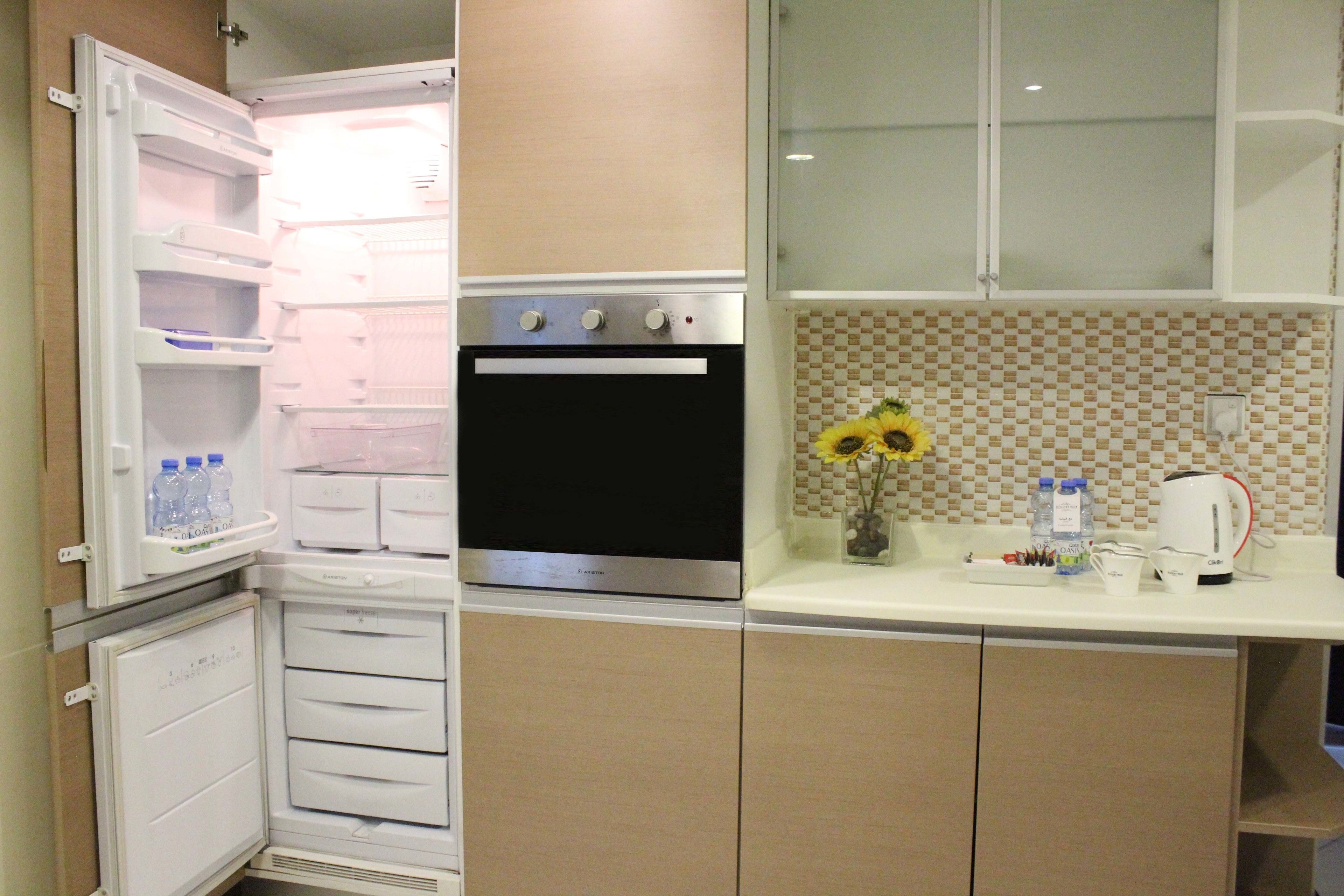 Eine Küche mit Einbauofen, Kühlschrank und einer Arbeitsplatte mit einer Vase mit Sonnenblumen.