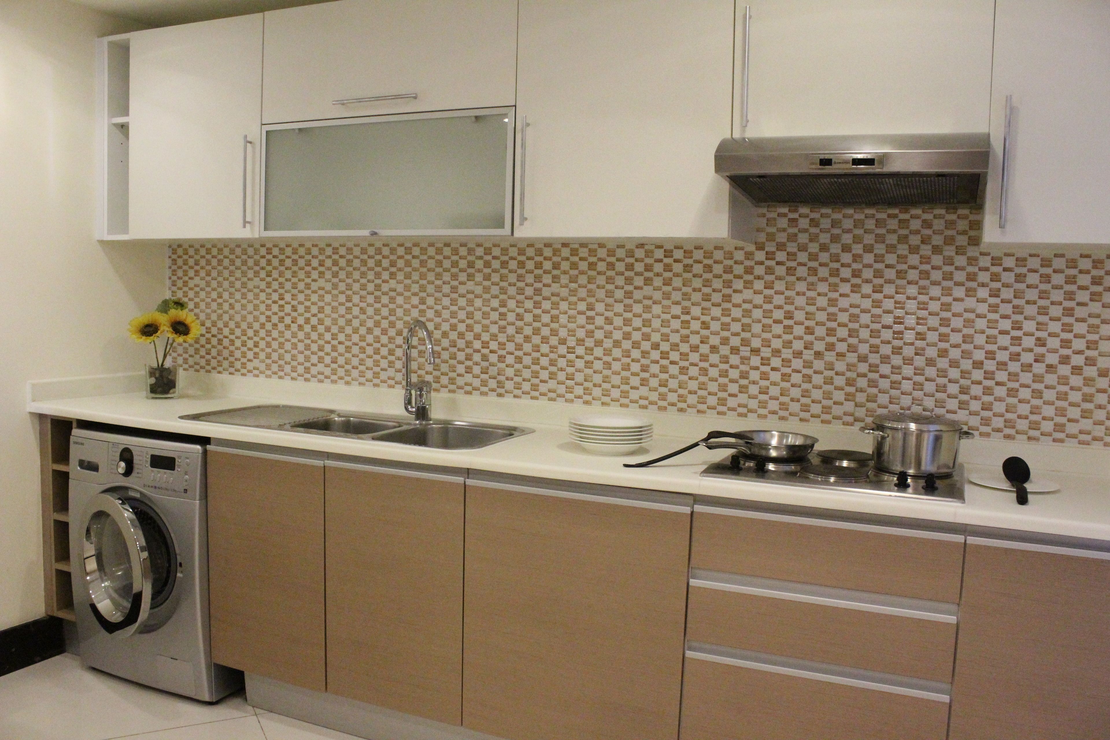 A compact kitchen with a washing machine, a sink, and a stove.