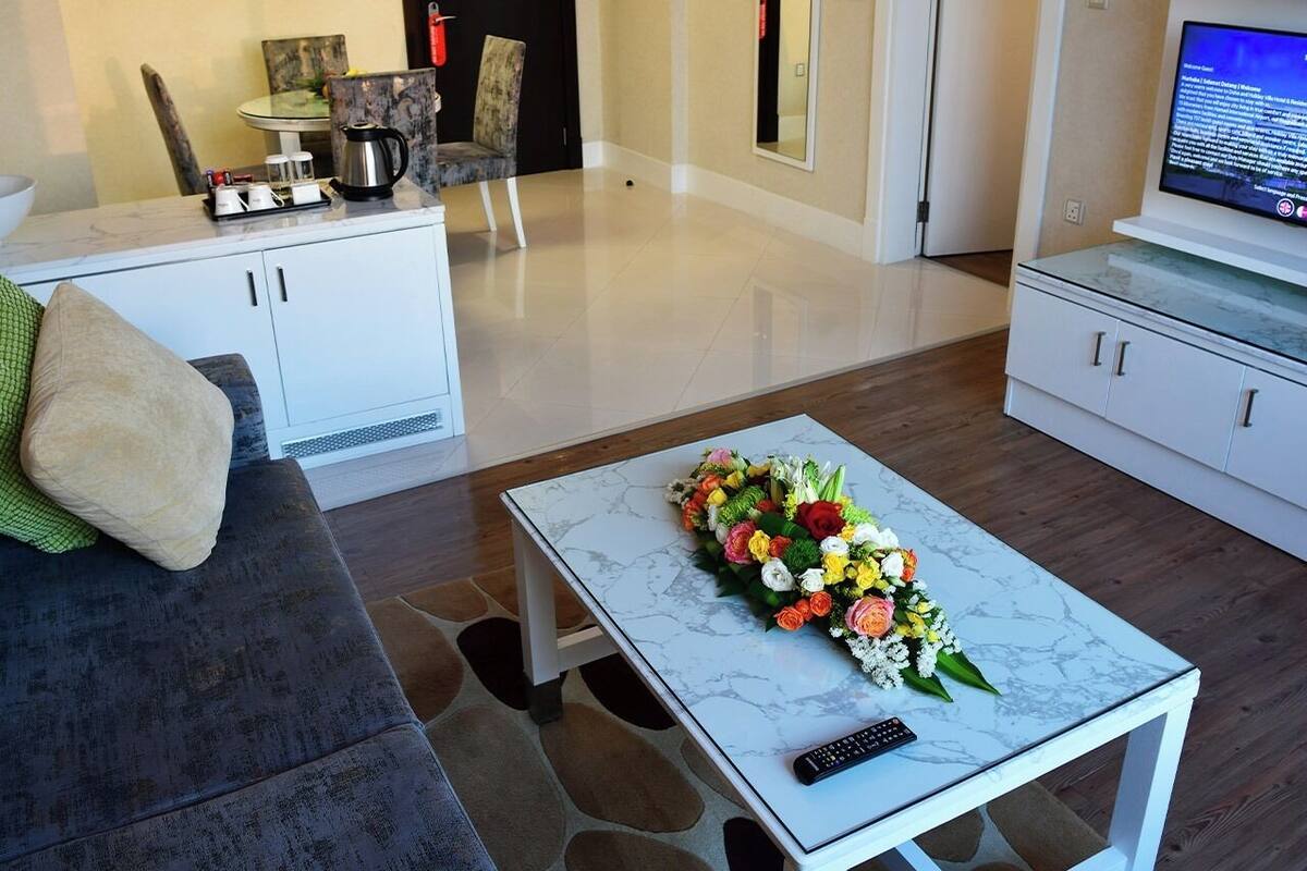 A modern living room with a marble coffee table, a floral centerpiece, a sofa, and a television.