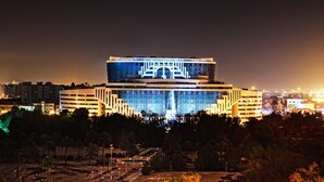 Un edificio moderno con una fachada de vidrio destacada y señalización iluminada.