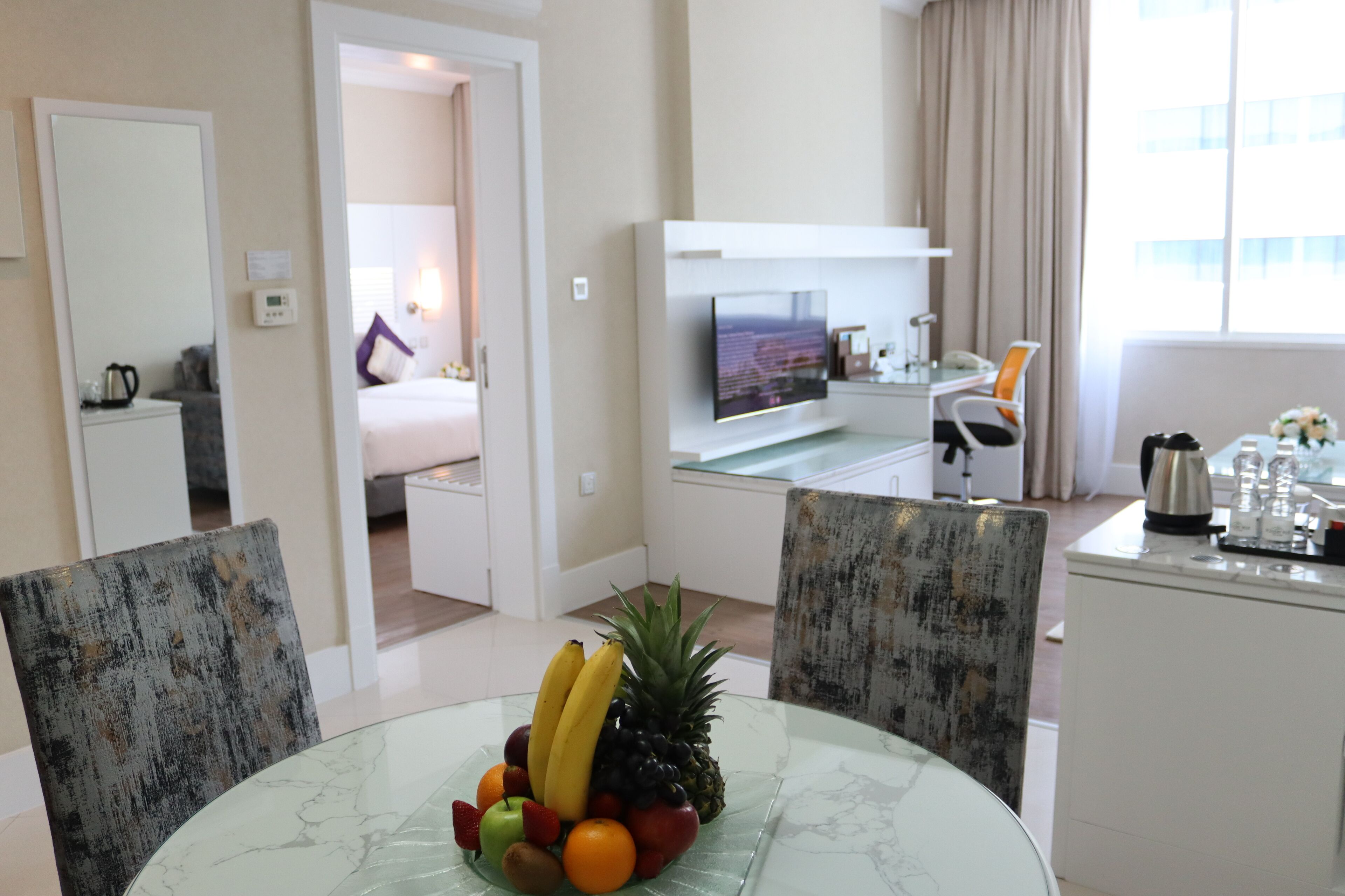 Una habitación de hotel con comedor, televisión, escritorio y cama.