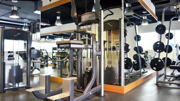 Un gimnasio con diversas máquinas de ejercicio, incluyendo un rack para sentadillas y bancos de pesas.