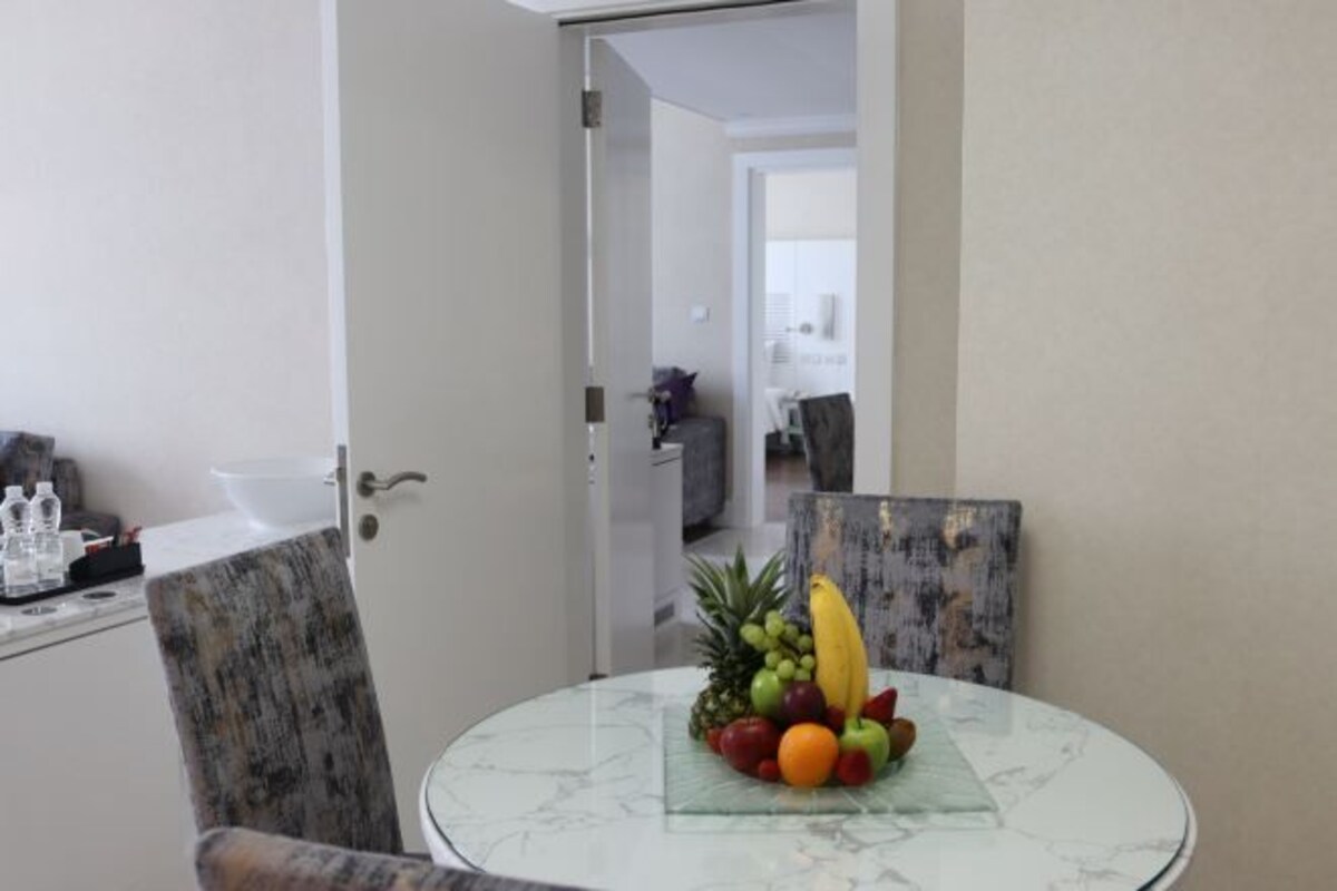 A dining area with a round glass table, a fruit bowl, and a chair.