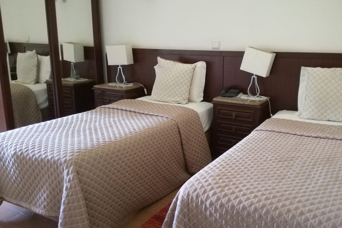 Two single beds with headboards, bedside tables with lamps, and a mirror on the wall.