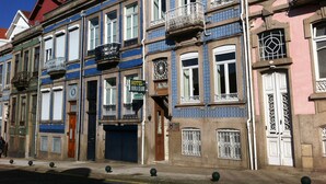 A row of colorful buildings with balconies, a visible hotel sign, and a closed garage door. - Hotel Miradaire Porto (Porto)
