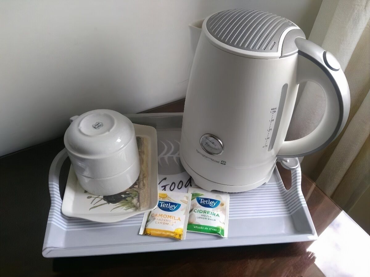 Una tetera eléctrica blanca, una tetera pequeña de color blanco, y dos paquetes de té Tetley sobre una bandeja.