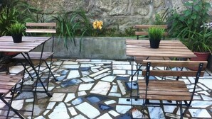 An outdoor patio with stone flooring, wooden tables and benches, and potted plants. - Hotel Miradaire Porto (Porto)