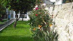 A garden with various plants and flowers, a stone wall, and a sidewalk. - Hotel Miradaire Porto (Porto)