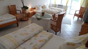 A cozy hotel room with two single beds, a small table with a lamp, a chair, and a potted plant. - Hotel Restaurant Linde (Otterstadt)