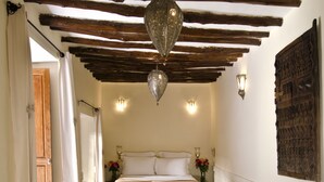 A bedroom with a bed, a sofa, a patterned rug, and a hanging light fixture.