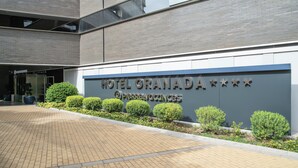 L’entrée d’un hôtel, avec une enseigne indiquant « HÔTEL GRANADA » et « Pierre & Vacances ».