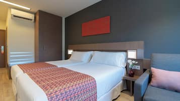 A hotel room with a large bed, a bedside table with a vase of flowers, and a red abstract painting on the wall.