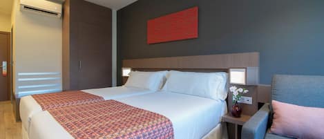 Habitación de hotel con una cama grande, una mesita de noche con un jarrón de flores y un cuadro abstracto rojo en la pared.
