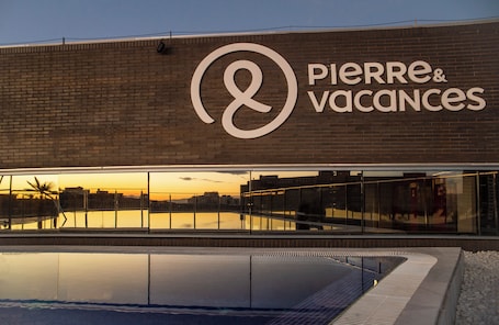 Una piscina al aire libre, sombrillas, sillones reclinables de piscina