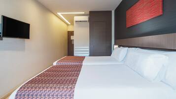 Una habitación de hotel moderna con una cama grande, un televisor de pantalla plana en la pared y una obra de arte abstracta roja sobre la cama.