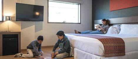 Una habitación de hotel con una cama, un televisor montado en la pared y una ventana.