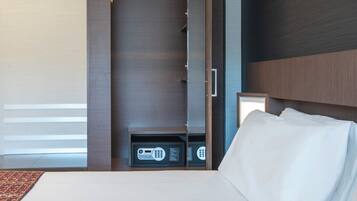 Een hotelkamer met een bed, een kledingkast en een klein kluisje.