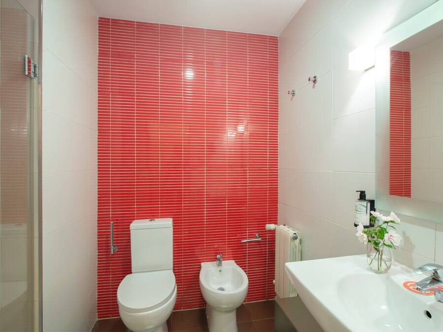Un baño con inodoro blanco, un bidé y un lavabo con espejo superior.