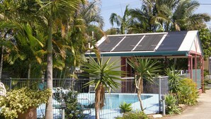 Une maison avec une piscine, entourée de palmiers et dotée d’un terrain clôturé.