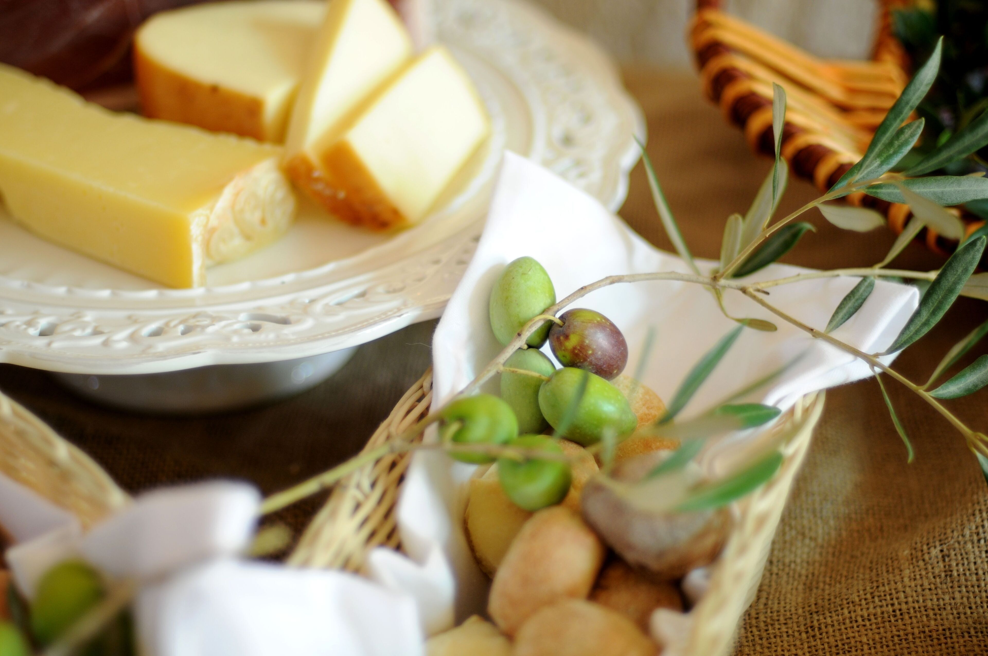 A cheese platter with various cheeses and olives on a table.