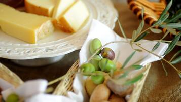 A cheese platter with various cheeses and olives on a table.