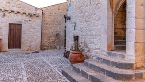 A cobblestone courtyard with stone buildings, a wooden door, and a potted plant. - Torre Don Virgilio Country Hotel (Modica)