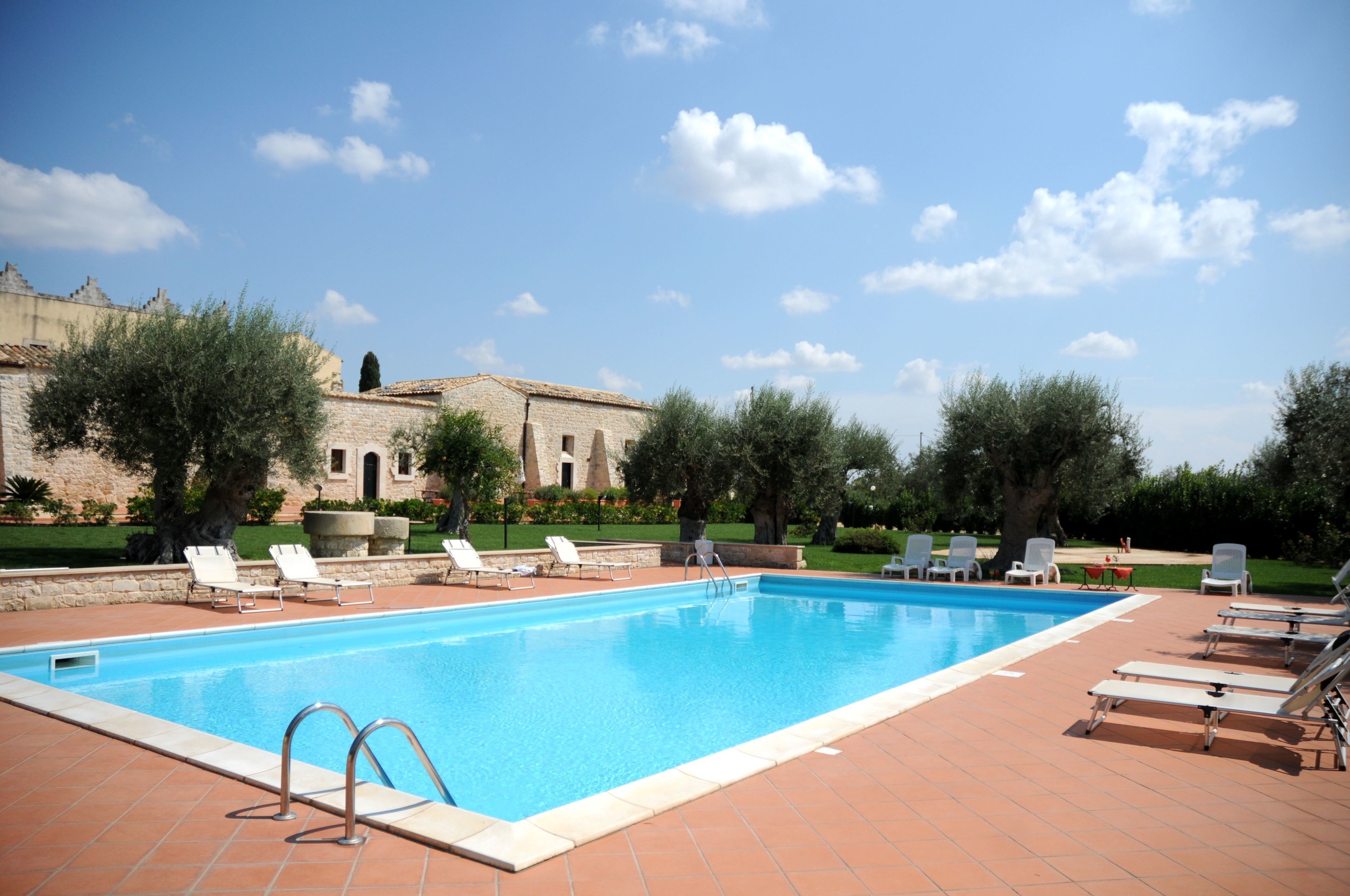 A swimming pool with lounge chairs and a stone building in the background.