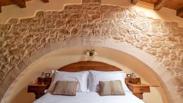 A bedroom with a stone arch ceiling, a wooden headboard, and two bedside tables with lamps.
