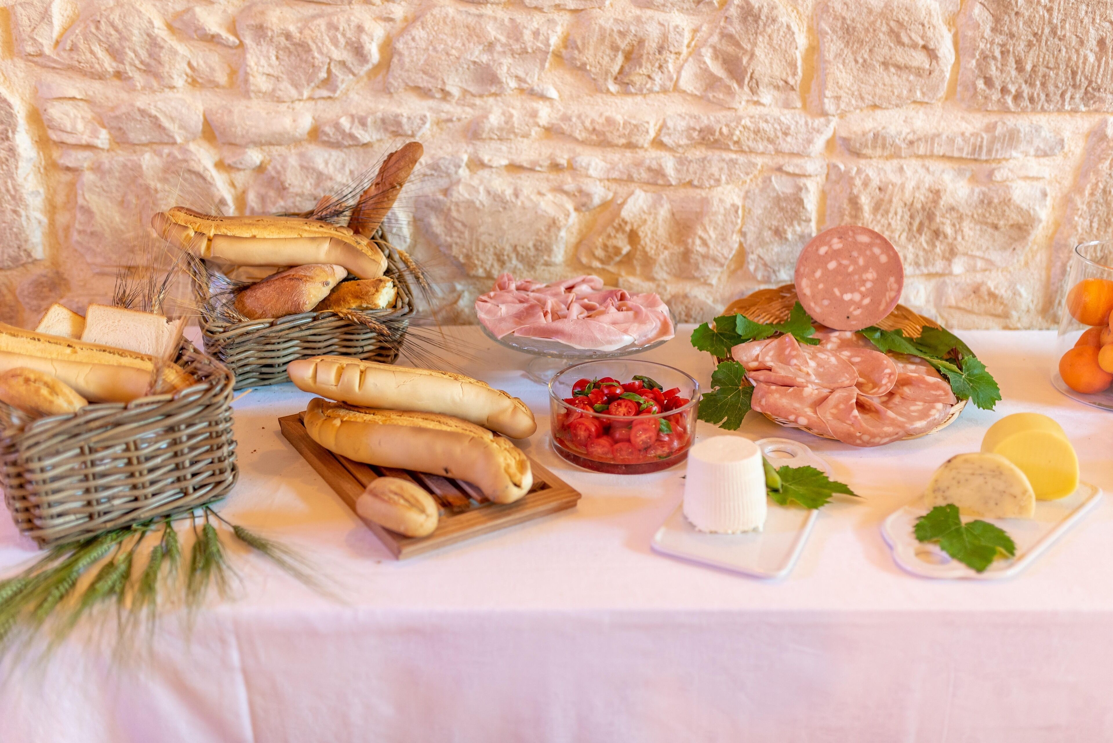 Een tafel met diverse etenswaren, waaronder brood, kaas en vleeswaren.