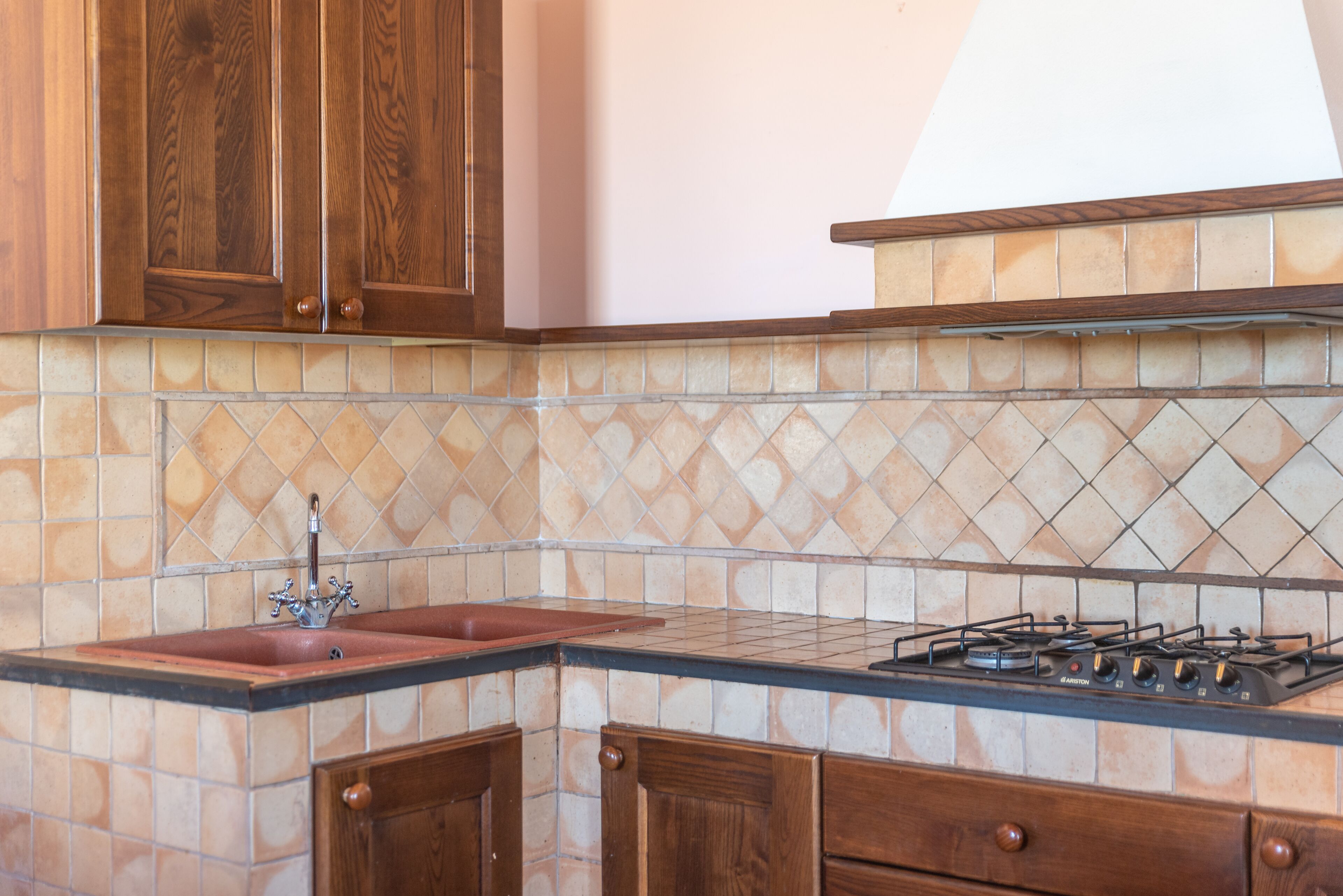 A kitchen with wooden cabinets, a tiled backsplash, a sink, and a gas stove.