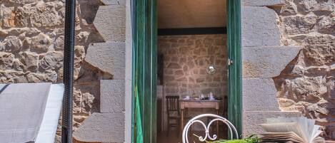 Una habitación con paredes de piedra, una mesa de comedor, sillas y un libro abierto.