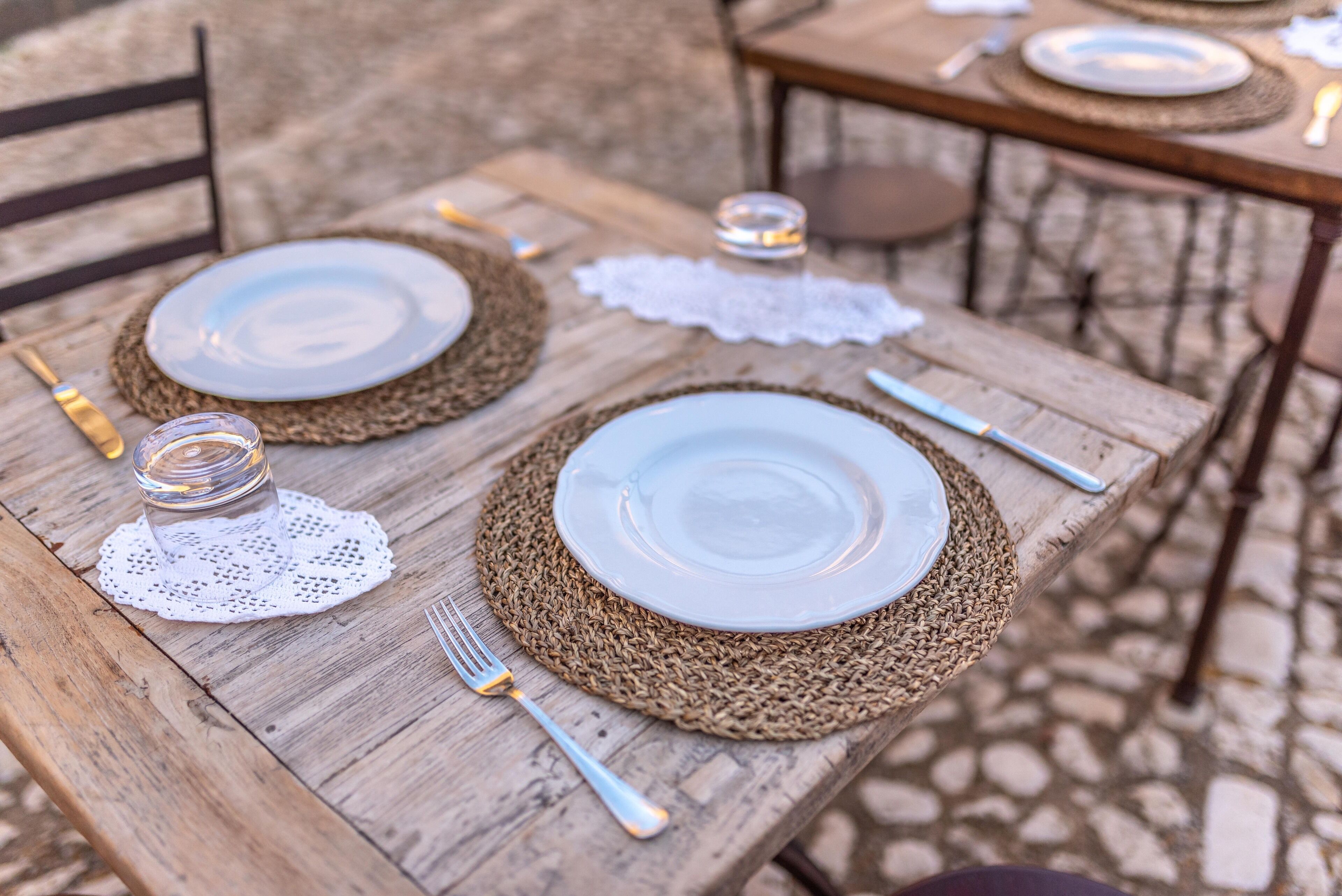 A wooden table set with plates, cutlery, and a glass jar.