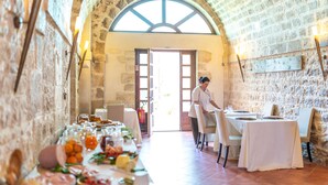 A restaurant with stone walls, a high arched doorway, and tables set for dining. - Torre Don Virgilio Country Hotel (Modica)