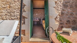 A stone building with a narrow entrance leading to a room with a table and chairs. - Torre Don Virgilio Country Hotel (Modica)