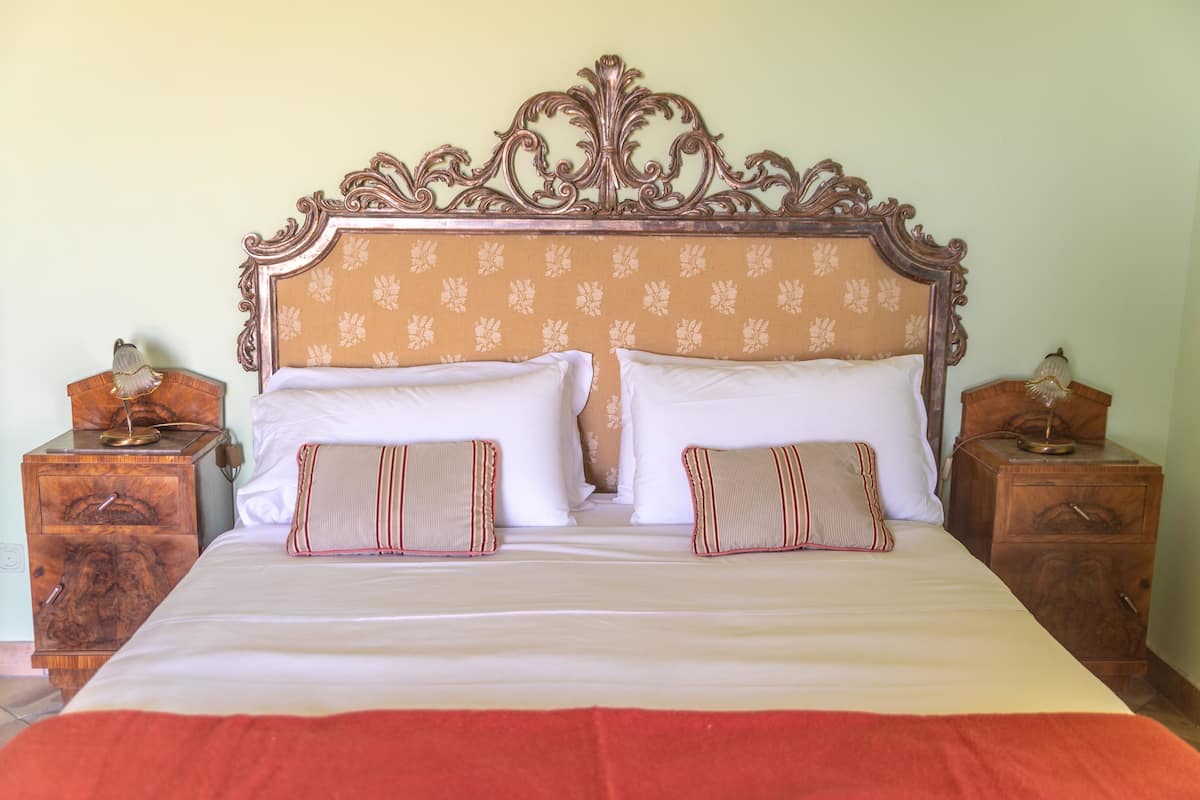A bed with a floral headboard, two bedside tables with lamps, and a red blanket.