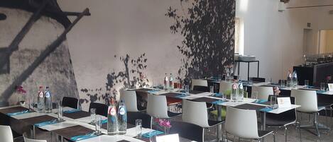 Un salón de conferencias con mesas dispuestas para reuniones, equipado con sillas, botellas de agua y tarjetas de identificación.