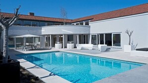 Une maison moderne dotée d’une piscine, d’une façade blanche et de grandes fenêtres.