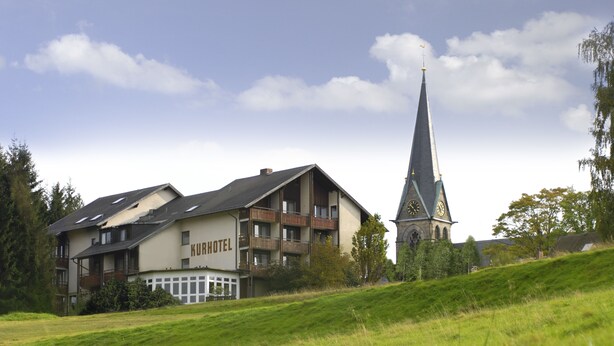 A hotel with a prominent clock tower and a sloped roof. - Gasthof Deutscher Adler & Hotel Puchtler (Bischofsgruen)