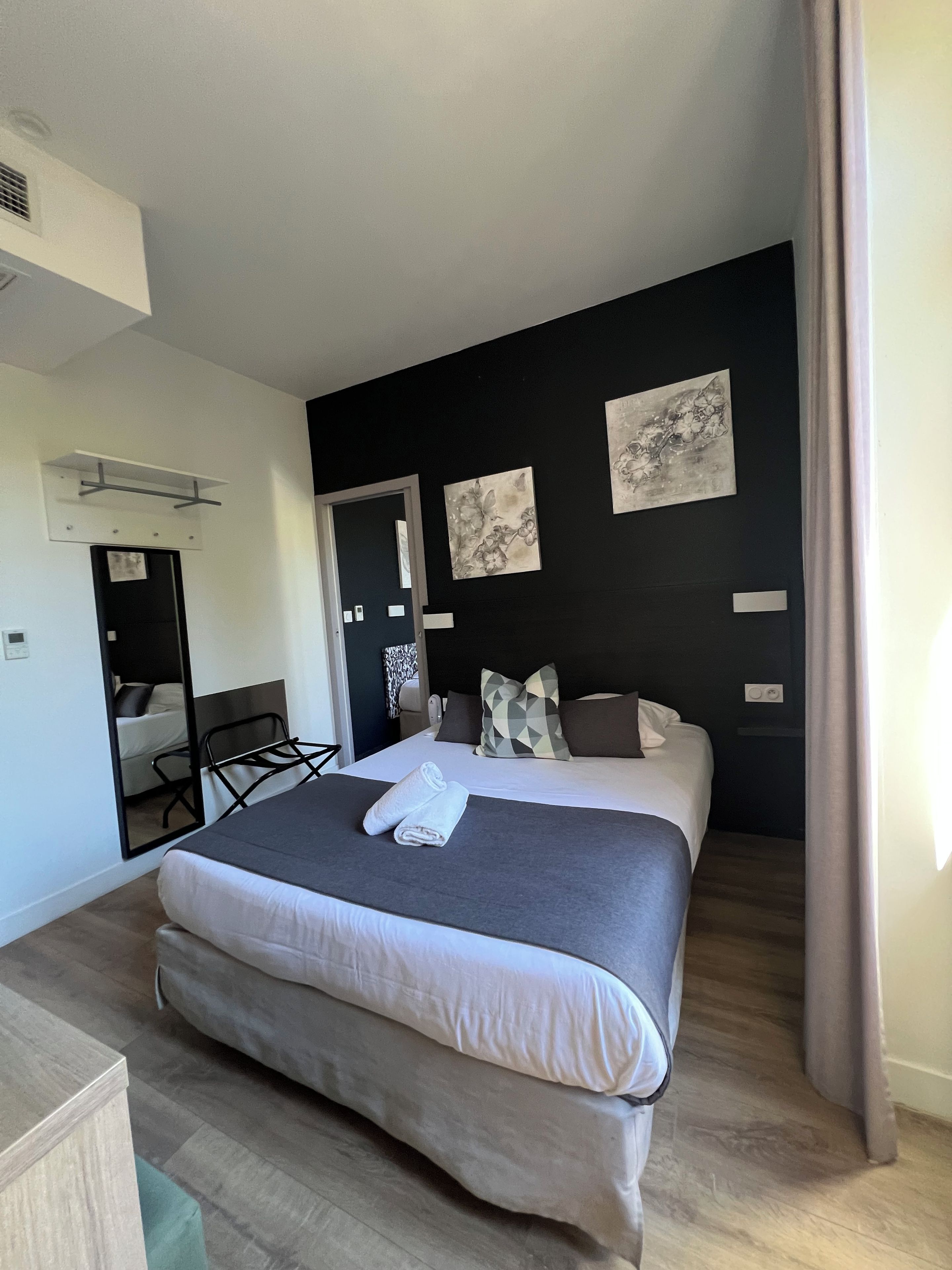A modern hotel room with a large bed, a desk, and a mirror.