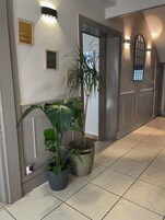 Un pasillo con una planta en maceta, una cita inspiradora enmarcada y un aplique de pared.