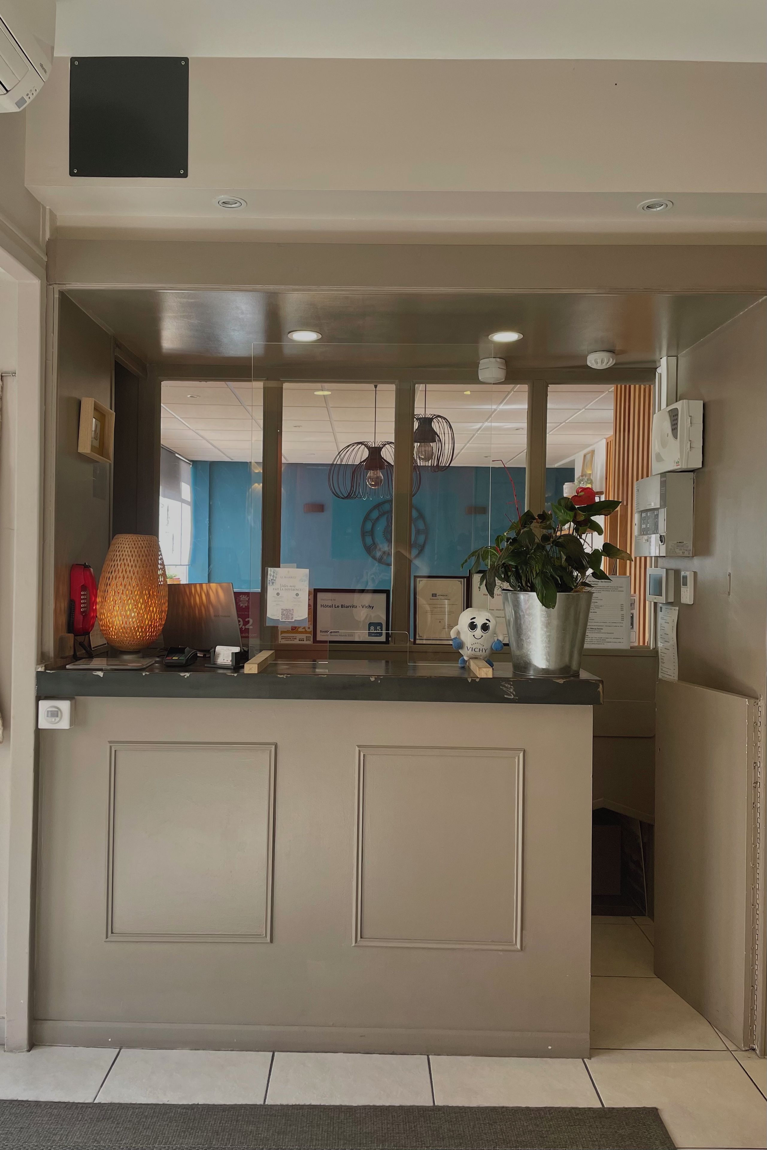 Un mostrador de recepción con diseño moderno, una planta en maceta y una lámpara decorativa.