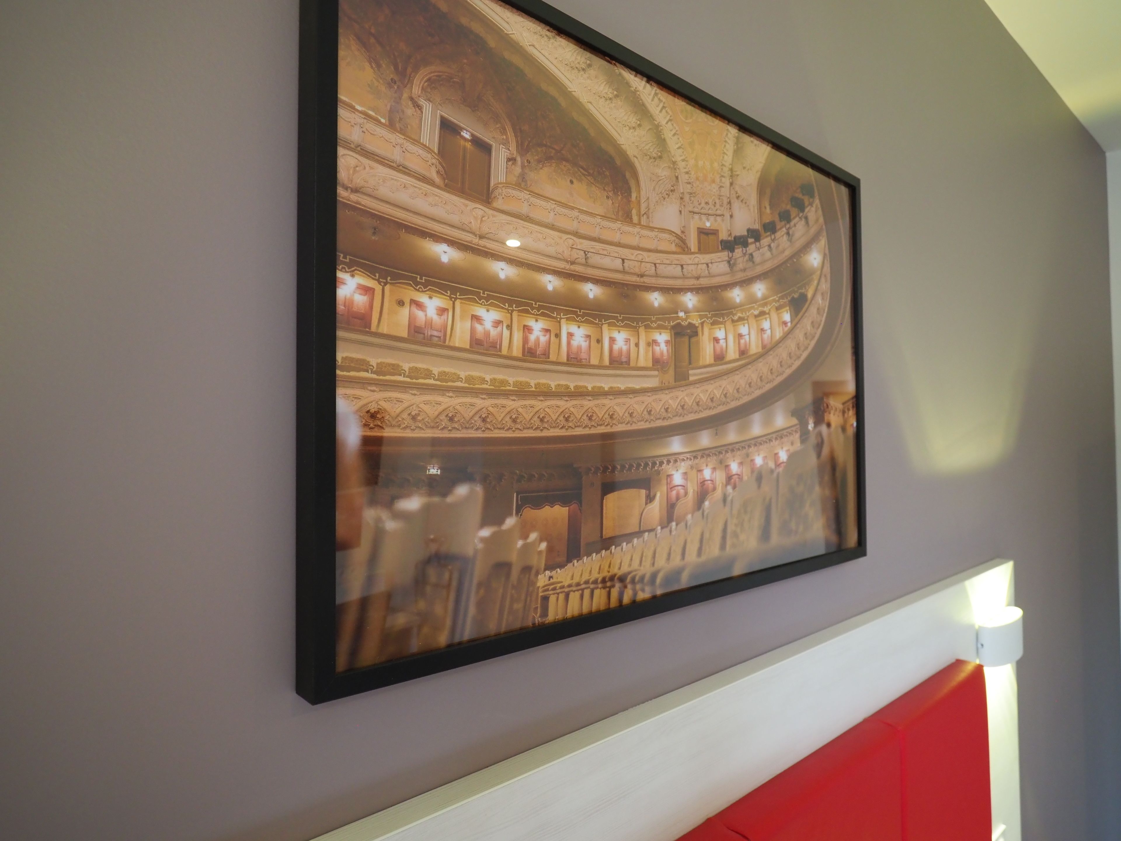 Een fotokader met het interieur van een versierd theater, met meerdere balkons en gedetailleerd plafondwerk.