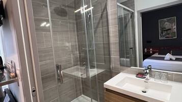 A modern bathroom with a glass-enclosed shower, a wooden vanity, and a large mirror.