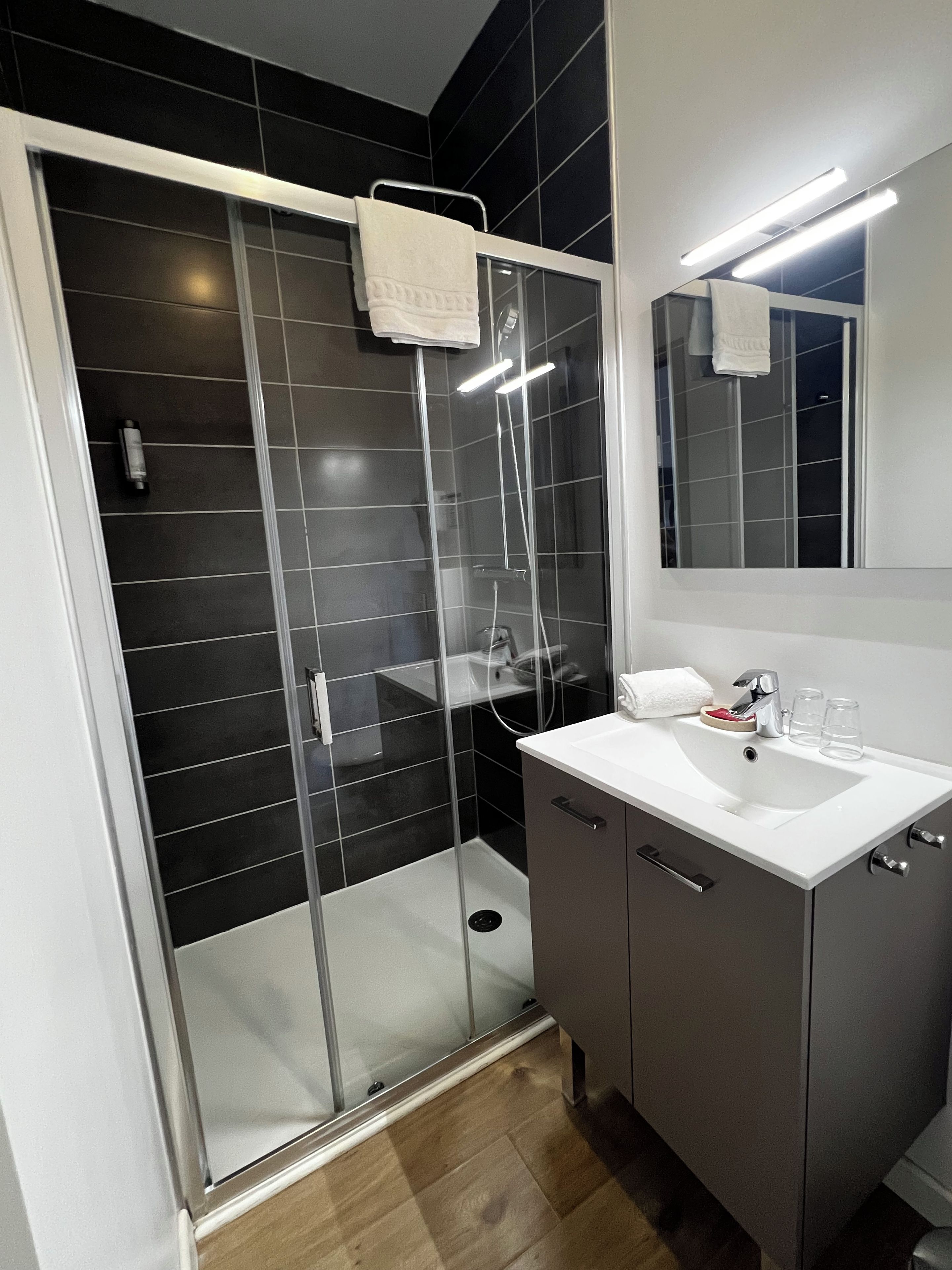 A modern bathroom with a glass-enclosed shower, a white sink, and a mirror above it.